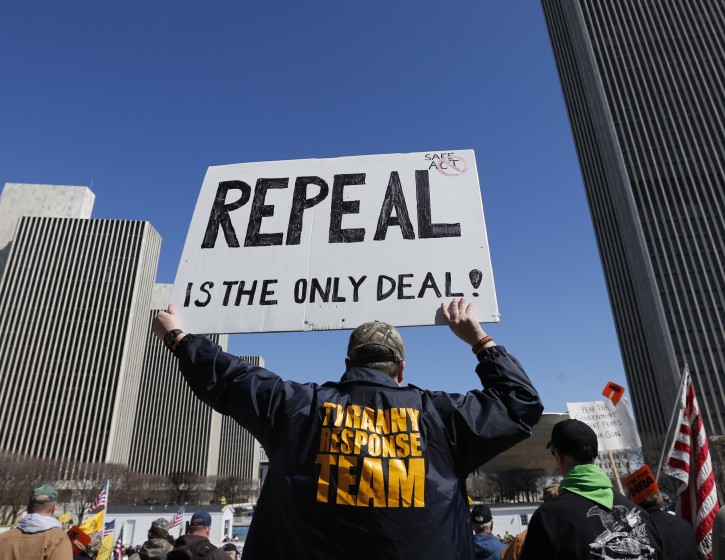 A gun rights activist holds a sign during a rally at the Empire State Plaza on Tuesday, April 1, 2014, in Albany, N.Y. Activists are seeking a repeal of a 2013 state law that outlawed the sales of some popular guns like the AR-15. The law championed by New York Gov. Andrew Cuomo has been criticized as unconstitutional by some gun rights activists. (AP Photo/Mike Groll)