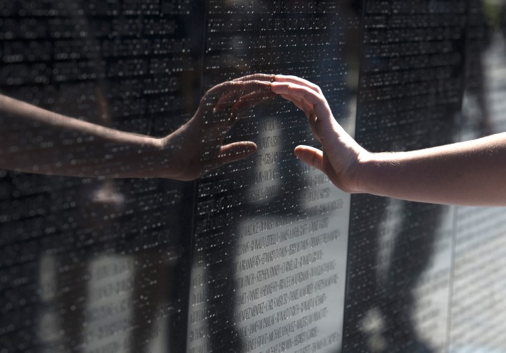 A visitor touches a name on the Vietnam Veterans Memorial in Washington, Sunday, May 25, 2014. (AP Photo/Molly Riley)