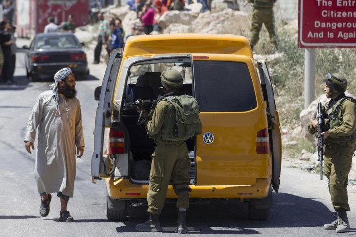 Israeli soldiers search a Palestinian vehicle at a checkpoint near the West Bank City of Hebron June 15, 2014. Israel said on Sunday Hamas militants had abducted three Israeli teenagers in the occupied West Bank, warning of "serious consequences" as it pressed on with a search and detained dozens of Palestinians. REUTERS/Baz Ratner 