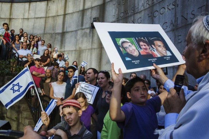 A boy holds a board with the likeness of three teenagers who had been kidnapped in Israel during a memorial service near the United Nations headquarters in New York June 30, 2014.  Reuters