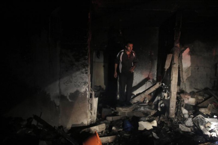 A man inspects the family home of an alleged abductor after a blast on the top floor in the West Bank City of Hebron July 1, 2014.  Reuters