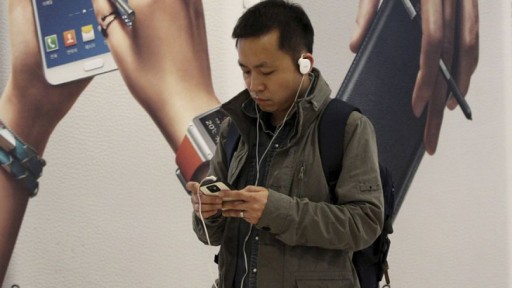 File: A man uses a smartphone near an advertisement for Samsung Electronics Co.'s Galaxy. (Photo AP)