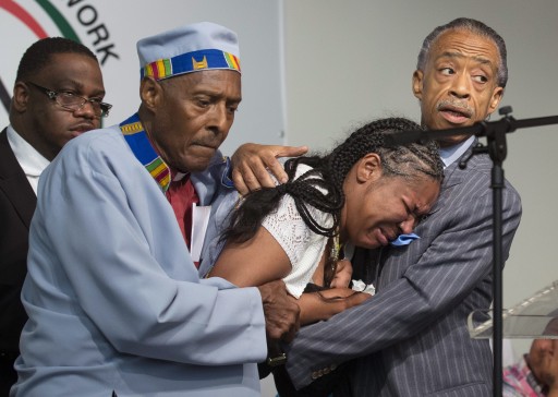 FILE - Esaw Garner, center, wife of Eric Garner, breaks down in the arms of Rev. Herbert Daughtry and Rev. Al Sharpton, right, during a rally at the National Action Network headquarters for Eric Garner, Saturday, July 19, 2014, in New York. Garner, 43, died Thursday, during an arrest in Staten Island, when a plain-clothes police officer placed him in what appeared be a chokehold while several others brought him to the ground and struggled to place him in handcuffs. (AP Photo/John Minchillo)