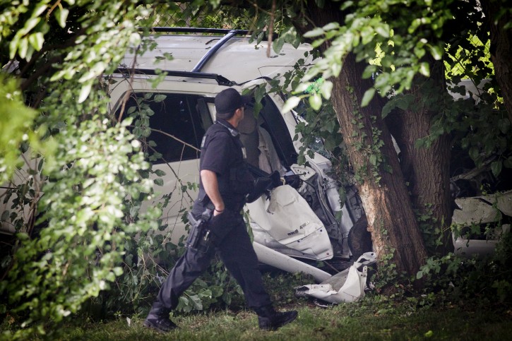 A police officer walks past the wreckage of a carjacked vehicle that police say hit a group of people on a corner in Philadelphia on Friday, July 25, 2014, killing three two children and critically injuring three other people. One of the children was pronounced dead at the scene and another at a hospital, Homicide Capt. James Clark said.  (AP Photo/Philadelphia Daily News, Alejandro A. Alvarez) 
