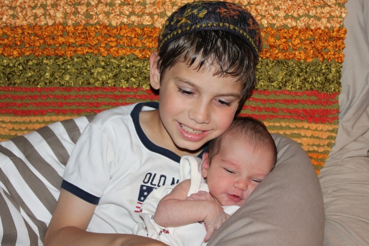 Seven year old Ehud Daniel Teitelbaum named after two soldiers  Sergeant Major Ehud Goldwasser of the IDF and Private First Class Daniel Agami of the United States Army holding his new baby brother Eyal Gilad Naftali 