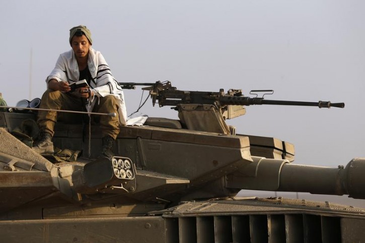 An Israeli soldier prays atop a tank near the border with the central Gaza Strip July 23, 2014.  Reuters