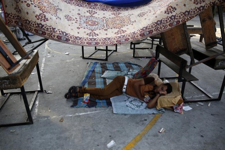 A Palestinian man sleeps in the courtyard of a United Nations-run school where 15 people were killed by explosions earlier in the day, at Beit Lahita in the northern Gaza Strip July 30, 2014. Reuters