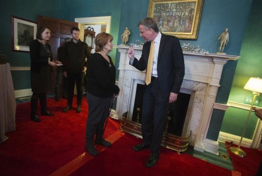 FILE - New York Mayor Bill de Blasio (R) speaks to a fellow visitor as he tours the library of Gracie Mansion during an open house event in New York January 5, 2014. REUTERS