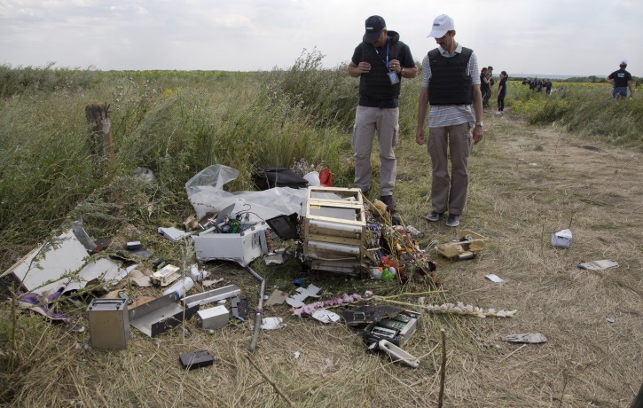 Members of the OSCE mission in Ukraine examine pieces of the crashed Malaysia Airlines Flight 17 in the village of Rassipne, Donetsk region, eastern Ukraine, Friday, July 25, 2014. (AP Photo/Dmitry Lovetsky)