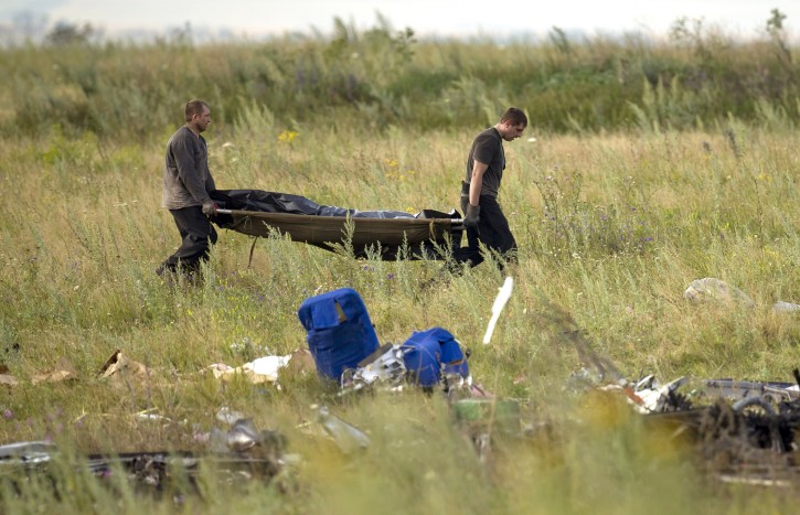 Men carry the body of a victim at the crash site of Malaysia Airlines Flight 17 near the village of Hrabove, eastern Ukraine, Saturday, July 19, 2014. (AP Photo/Vadim Ghirda)