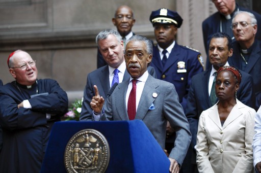 Reverend Al Sharpton speaks next to Cardinal Timothy Dolan (L) and New York City mayor Bill de Blasio (2nd L) during a news conference after an interfaith roundtable meeting on strengthening police-community relations with members of the city's clergy in Manhattan, August 20, 2014.  REUTERS/Eduardo Munoz