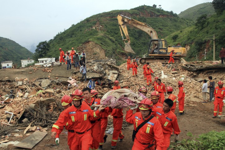 Rescue workers remove a dead body from the remains of a collapsed building at the epicenter of an earthquake that struck the town of Longtoushan in Ludian county in southwest China's Yunnan province Monday, Aug. 4, 2014.  Rescuers dug through shattered homes Monday looking for survivors of a strong earthquake in southern China's Yunnan province that toppled thousands of homes on Sunday, killing hundreds and injuring more than a thousand people. (AP Photo) 