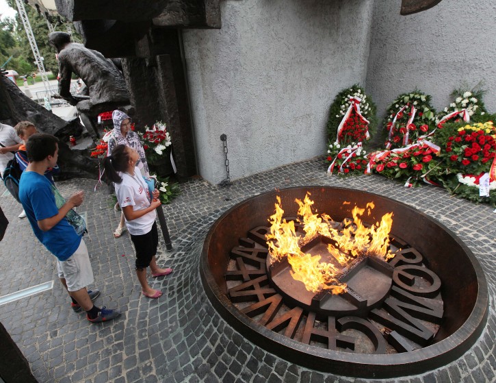 People stand at  the Warsaw Uprising monument  in Warsaw,  Friday, Aug. 1, 2014. On the 70th anniversary of the Warsaw Uprising, Poland is honoring the fighters and victims of the rebellion against Nazi Germans by laying wreaths, sounding sirens and singing insurgent tunes. On Aug. 1, 1944, thousands of poorly-armed city residents rose up against the German forces to try to take control of the city ahead of the advancing Soviet army. They held on for 63 days before being forced to surrender. Almost 200,000 people were killed. The Nazis expelled the survivors and set the city ablaze. (AP Photo/ Czarek Sokolowski)