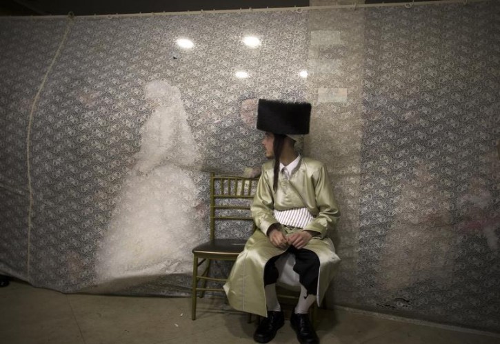 Ironically VINnews has found that Reuters has covered the same wedding showing in this image Rivka Krauss walking behind a curtain towards her groom Aaron Krauss (front) after their traditional wedding ceremony in the Mea Shearim neighbourhood of Jerusalem February 18, 2014. (REUTERS/Ronen Zvulun )