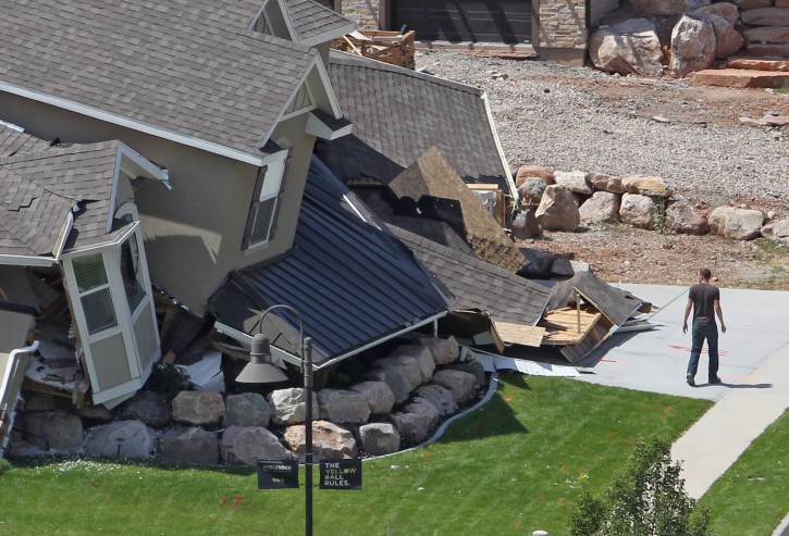 A man looks at a home destroyed by a landslide in a hillside community of North Salt Lake, Utah, Tuesday, Aug. 5, 2014. One home was destroyed and 27 others were evacuated after a landslide early Tuesday struck an upscale suburban Salt Lake City community, where officials had worried for nearly a year about cracked soil on the hillside above the houses. (AP Photo/Rick Bowmer)