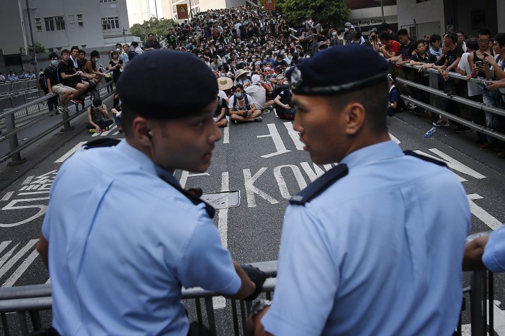 Pro-democracy protesters sit on a road as they face-off with local police, Monday, Sept. 29, 2014 in Hong Kong. Pro-democracy protesters expanded their rallies throughout Hong Kong on Monday, defying calls to disperse in a major pushback against Beijing's decision to limit democratic reforms in the Asian financial hub. (AP Photo/Wong Maye-E)