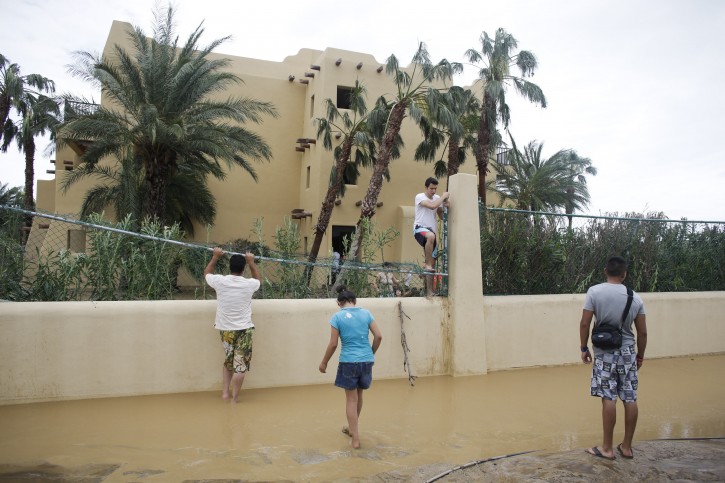 Tourist Cesar Calzada, center, of Mexico City, climbs over a fence of the Riu resort to get out of the hotel and go search for food after Hurricane Odile severely damaged the hotel in Los Cabos, Mexico, Monday, Sept. 15, 2014. Hurricane Odile blazed a trail of destruction through Mexico's Baja California Peninsula that leveled everything from ramshackle homes to big box stores and luxury hotels, leaving roads and entire neighborhoods as disaster zones. (AP Photo/Victor R. Caivano)