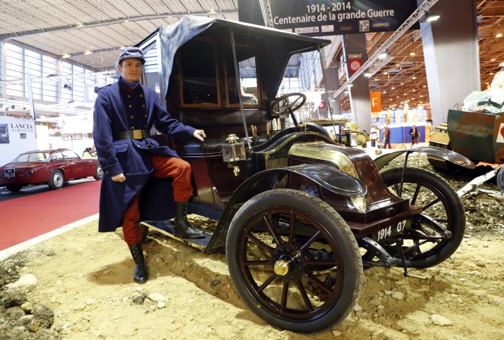 In this Wednesday, Feb. 5, 2014 file photo, an actor dressed like a WWI soldier poses in front of a 1914 Renault AG1, known as Taxi de la Marne, during the Retromobile vintage cars exhibition, in Paris. Weeks after World War I erupted, with the capital under threat from German invaders, French military chiefs devised a novel way for soldiers to travel to the front lines: by taxi. To that end, they requisitioned hundreds of cabs, and their drivers were charged with the risky mission of getting thousands of troops to the battlefield. (AP Photo/Jacques Brinon, File)