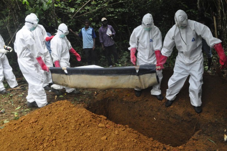 In this Saturday, Oct. 18, photo a burial team in protective gear bury the body of a woman suspected to have died from Ebola virus in Monrovia, Liberia. (AP Photo/Abbas Dulleh, File)