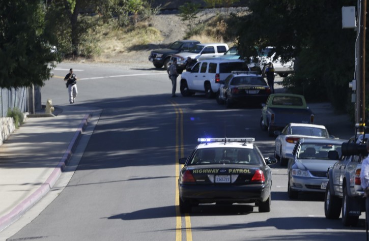 A California Highway Patrol car and other law enforcement vehicles set up a roadblock near Placer High School leading to a rural area where authorities are searching for an assailant, in Auburn, Calif.,  who shot three sheriff's deputies in two Northern California Counties, Friday, Oct. 24, 2014.  AP