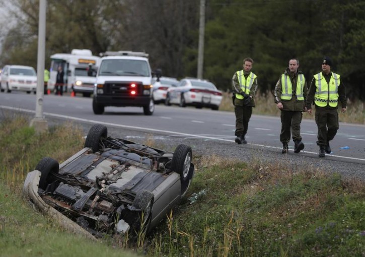 A Surete du Quebec (SQ) officer investigates an overturned vehicle in Saint-Jean-sur-Richelieu, Quebec October 20, 2014. Two Canadian soldiers were injured in a hit-and-run in the province of Quebec on Monday by a male driver who was later shot by police officers, said a spokesman for the Surete du Quebec, the provincial police force. REUTERS/Christinne Muschi