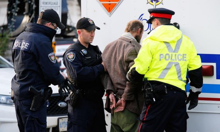 Police officers search a man arrested after approaching police tape near the Canada War Memorial while Prime Minister Stephen Harper paid respect to Cpl. Nathan Cirillo at the Memorial in Ottawa October 23, 2014.  Reuters