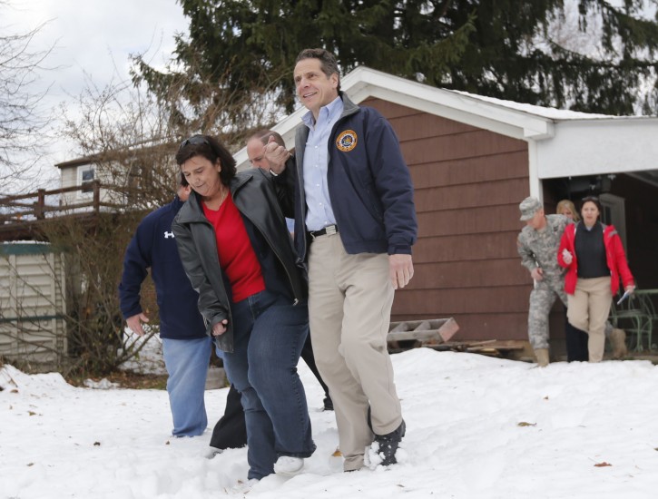 FILE- In this Nov. 24, 2014 file photo, New York Gov. Andrew Cuomo, right, helps resident Nancy Barletta through the snow at her house while surveying the aftermath of a lake-effect snowstorm in West Seneca, N.Y. Cuomo has criticized the National Weather Service for its forecasts of the storm, and said the state is creating its own weather monitoring system. (AP Photo/Mike Groll, File )