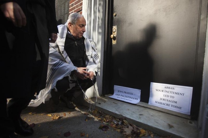Rabbi Avi Weiss places signs at the door of the Palestine Mission to the United Nations in New York, as demonstrators rally across the street over a deadly attack on a Jerusalem synagogue, November 18, 2014. 