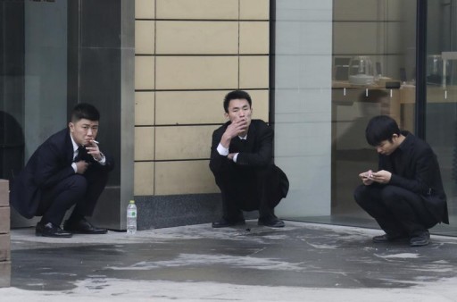 FILE - Employees smoke outside an office building in Beijing, November 25, 2014. Reuters