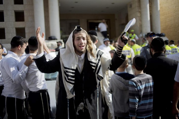An ultra-Orthodox Jewish man prayers as Israeli rescue workers clean the scene of a shooting attack in a Synagogue in Jerusalem, Tuesday, Nov. 18, 2014. (AP Photo/Ariel Schalit)