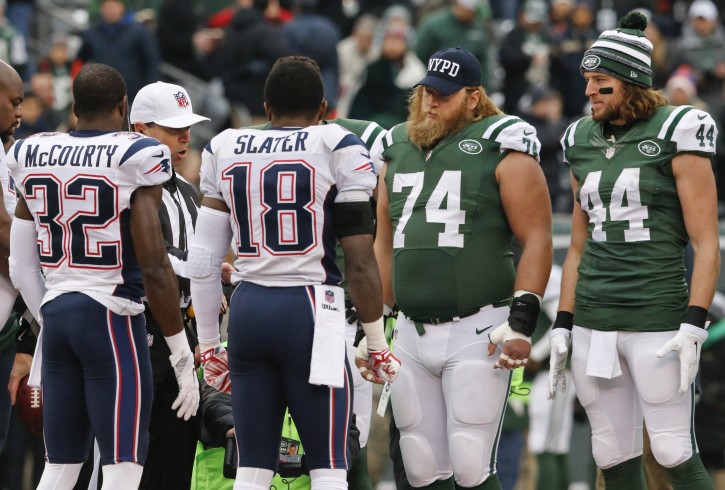 New York Jets center Nick Mangold (74) wears an NYPD cap during the coin toss with teammate Zach Sudfeld (44) and New England Patriots' Devin McCourty (32) and Matthew Slater (18) before an NFL football game Sunday, Dec. 21, 2014, in East Rutherford, N.J. (AP Photo/Julio Cortez)