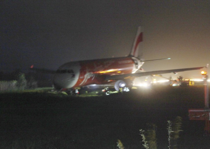 An AirAsia passenger plane sits on the grassy portion of the runway after overshooting upon landing in windy weather at Kalibo airport in Kalibo township, Aklan province in central Philippines Tuesday, Dec. 30, 2014. (AP Photo/Jun Aguirre)