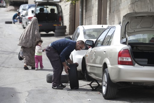 File: A Palestinian man replaces a flat tire in the East Jerusalem Arab neighborhood of Beit Hanina, 24 March 2014. Tires of dozens of cars were punctured overnight in a so-called Price Tag attack. EPA/ABIR SULTAN