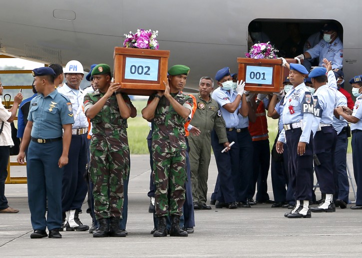 Indonesian military personnel carries two coffins with the remain of bodies recovered from the AirAsia crash site as they arrive at Juanda Airport, in Surabaya, Indonesia, 31 December 2014. EPA/MADE NAGI