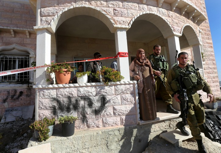 epa04543676 Israeli soldiers leave the home of a Palestinian family in the West Bank village of Yatta, near Hebron, 31 December 2014, after it was reportedly torched. Hebrew graffiti was left on the outside of the home.  EPA