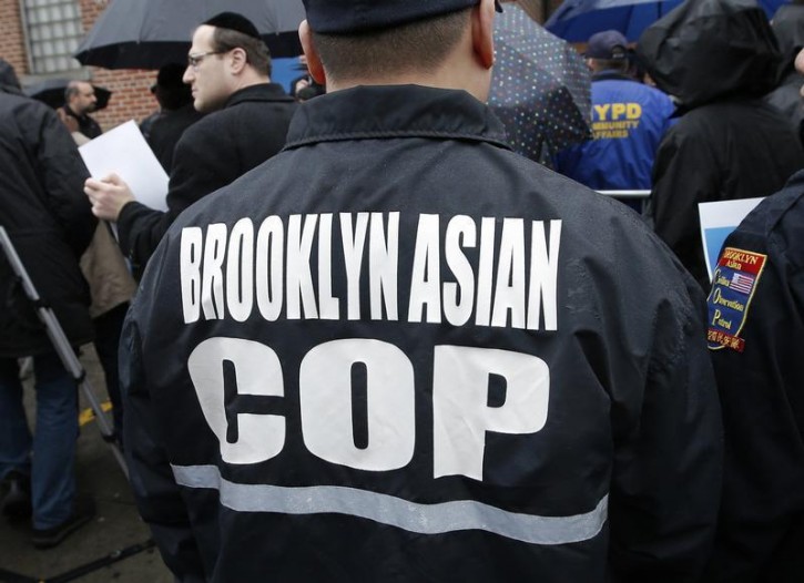 FILE - A member of the Brooklyn Asian Civilian Observation Patrol stands with others outside the 66th Police Precinct headquarters in Brooklyn, New York, December 23, 2014, during a rally with members of the Jewish community in support of police after two police officers were fatally shot in the Brooklyn borough of New York Saturday. Reuters