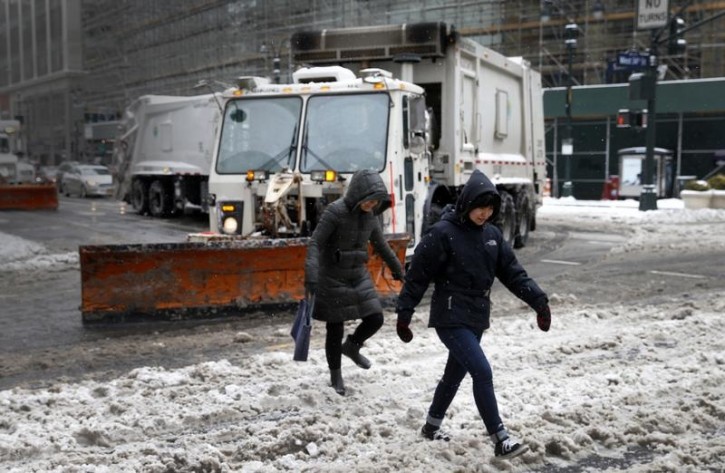 People pass in front of snow plows clearing  West 34th street in New York city as the city slowly returned to normal after being hit by winter storm Juno January 27, 2015.REUTERS