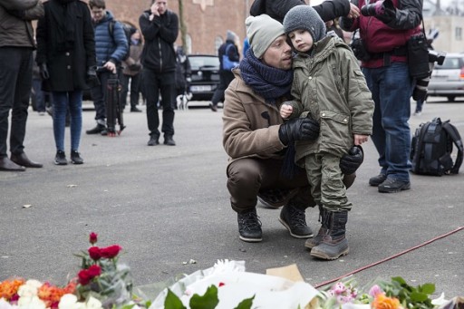 A man and a child are pictured behind flowers outside the main Synagogue in Copenhagen on February 15, 2015 following two fatal attacks in the Danish capital, a month after the Paris attacks.FP PHOTO / ODD ANDERSEN      