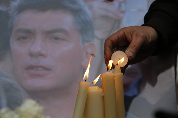 People light candles in memory of Boris Nemtsov, seen behind, at the monument of political prisoners 'Solovetsky Stone' in central St.Petersburg, Russia, Saturday, Feb. 28, 2015. Nemtsov was gunned down Saturday near the Kremlin, just a day before a planned protest against the government. (AP Photo/Dmitry Lovetsky)