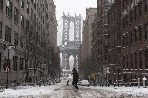 The Manhattan Bridge is seen in the background as commuters make their way through the streets of Dumbo after a snow storm in New York January 27, 2015. REUTERS