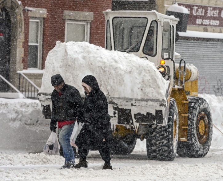 People walk in the heavy snow as a loader carries snow in Boston, Massachusetts, USA, 02 February 2015.  EPA