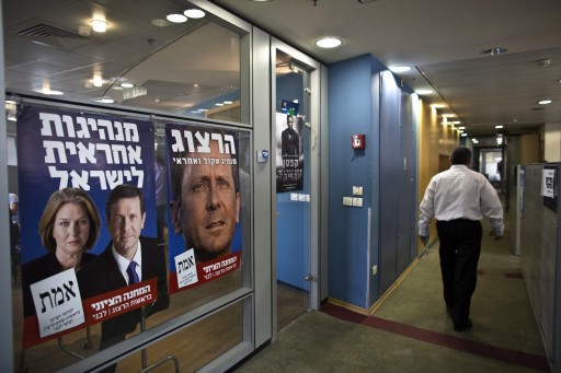 A man walks past election campaign posters depicting Tzipi Livni and Isaac Herzog, heads of the centrist Zionist Union party, at the party's headquarters in Tel Aviv March 11, 2015. REUTERS/Nir Elias