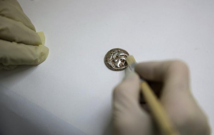 A recently uncovered coin from the time of Alexander the Great is displayed in Jerusalem March 9, 2015. Cave explorers in Israel have uncovered a small trove of coins and jewellery from the time of Alexander the Great that archaeologists believe was hidden by refugees during an ancient war.The 2,300-year-old treasure was the first of its kind to be found from the period of the conquerer, said Eitan Klein of the Israel Antiquities Authority. REUTERS/Ronen Zvulun