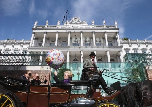 Passengers wave to journalists from a traditional Fiaker horse-carriage as they pass Palais Coburg hotel, the venue of nuclear talks in Vienna April 22, 2015.   REUTERS/Heinz-Peter Bader