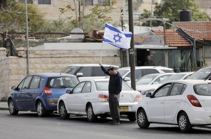 A man holds Israel's national flag as he stands still during the sounding of a two-minute siren marking Holocaust Remembrance Day in Jerusalem April 16, 2015. Israel on Thursday marks its annual memorial day commemorating the six million Jews killed by the Nazis during World War Two.   REUTERS/Ammar Awad