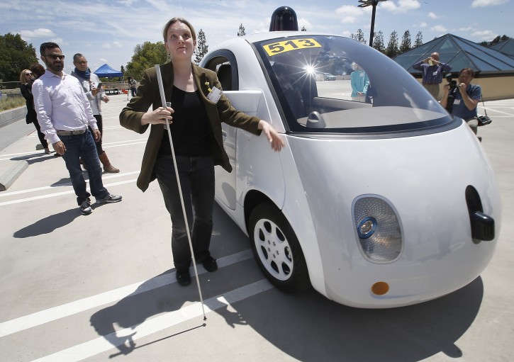 In this May 13, 2015 photo, Jessie Lorenz, of San Francisco, touches the new Google self-driving prototype car during a demonstration at the Google campus in Mountain View, Calif.  The car, which needs no gas pedal or steering wheel, will make its debut on public roads this summer. (AP Photo/Tony Avelar)