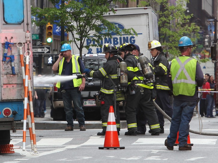 Firefighters spray water on a fire in a manhole in New York on Wednesday, May 6, 2015. An explosion in the manhole near Penn Station in midtown Manhattan snarled traffic in the area. Fire officials say there were no injuries. (AP Photo/Peter Morgan)