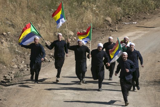 Members of the Druze community carry flags as they run towards the border fence between Syria and the Israeli-occupied Golan Heights, near the Druze village of Majdal Shams, in this June 16, 2015 file photos.  REUTERS/Baz Ratner/Files