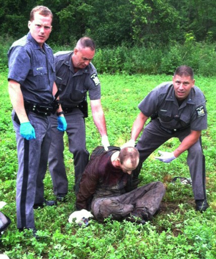 Police stand over David Sweat after he was shot and captured near the Canadian border Sunday, June 28, 2015, in Constable, N.Y. (AP Photo)