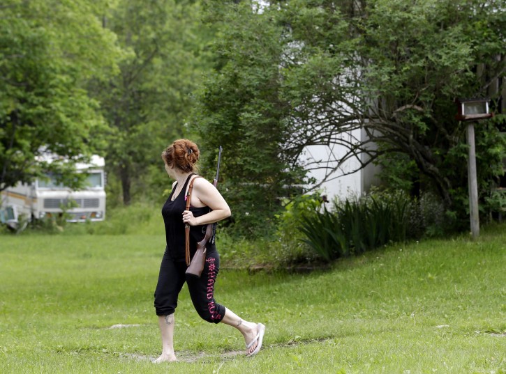 Jennifer Hilchey-Reyell watches the tree line as she carries a .22 rifle walking from her mother's house to her own house near Dannemora, N.Y., Thursday, June 11, 2015. Hilchey-Reyell has been keeping a gun close at hand since the escape of two prisoners from the maximum-security Clinton Correctional Facility near her home. (AP Photo/Seth Wenig)